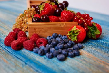 Taze meyve, çilek, ahududu, kuş üzümü, kiraz şeklinde ortaya konulan ahşap masa