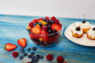 Muffin yalan büyük beyaz tabak ayakta bir derin cam kase salata taze çilek yanında tarih