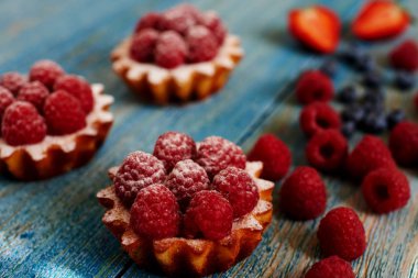Lezzetli mini turta yulaf ezmesi taze ahududu ve muhallebi ahşap bir mavi masa üzerinde yapılmış. Ev yapımı bir tatlı lezzetli mini kek yaptı. Sağlıklı snack. Yararlı kahvaltı. Seçici odak.