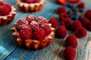 Lezzetli mini turta yulaf ezmesi taze ahududu ve muhallebi ahşap bir mavi masa üzerinde yapılmış. Ev yapımı bir tatlı lezzetli mini kek yaptı. Sağlıklı snack. Yararlı kahvaltı. Seçici odak.