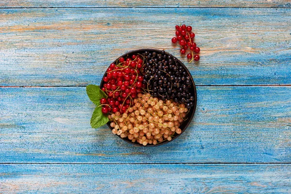 On the blue table textural of aged wood, it is full of dishes with fresh berries