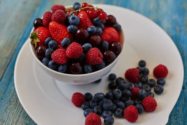 On a blue vintage kitchen table, the cook served berry dessert of various ripe berries