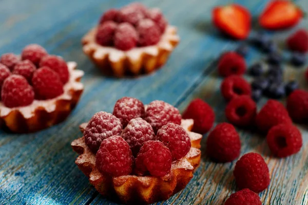 Lezzetli mini turta yulaf ezmesi taze ahududu ve muhallebi ahşap bir mavi masa üzerinde yapılmış. Ev yapımı bir tatlı lezzetli mini kek yaptı. Sağlıklı snack. Yararlı kahvaltı. Seçici odak.