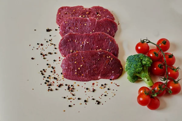 在白色的切桌子上 肉被切成不同的香料和草药调味的牛排 — 图库照片
