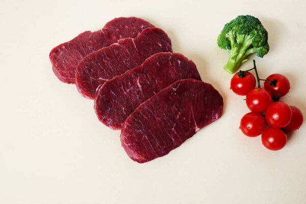 Uncooked set of ingredients on white background.Vegetables and pieces of meat. Cherry tomato, broccoli and beef slices for tasty dinner.