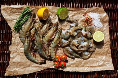 Kireç ve limon iki yarısı kapatmak için kesmek hafif kahverengi parşömen kağıt üzerine karides vardır