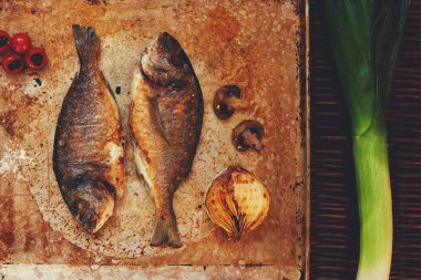 Cook two small fish gilt-head bream  baked in the oven until crisp hipster filter color clipart