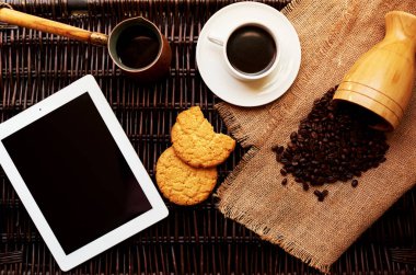 Plaka, taze kahve ve bir yuvarlak yulaf ezmeli kurabiye karanlık hasır rattan masa üzerinde hafif bir kahvaltı servis edilir