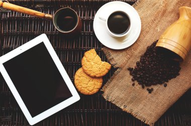 Hasır dijital tablet, aromalı kahve ve ev yapımı bisküvi ile küçük bir kupa üstten görünüm