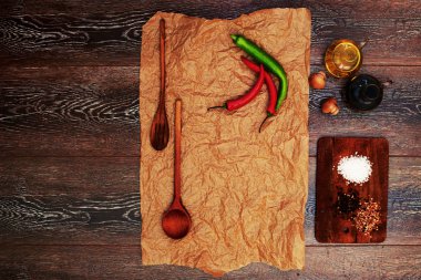 Antika ahşap masa boş fırın kağıt, taze biber, baharatlar, zeytin yağı ve ahşap mutfak eşyaları ile tarifleri ile. Üstten görünüm kopya alanı ile. Mutfak günlüğü konsepti. Seçici odak.