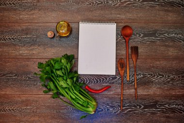 Reklam, ahşap bir masa mutfak, ahşap çatal bıçak takımı, zeytin yağı, red hot chili peppers yanında yatan defter için bir yer