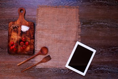 Ahşap mutfak dijital tablo bir tablet yakınındaki bir ahşap tahta kesme sebze kurulu kiraz domates üzerinde yatıyor.