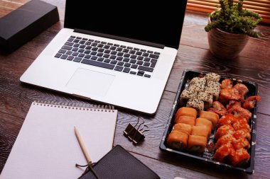 Başı işleri, defter, kalem, smartphone ile işyeri. İş - ofis zaman eksikliği, Hızlı öğle yemeği. Erişte ve suşi dizüstü yanında masaüstünde ayarla. Çalışma ve yaşam tarzı arka plan