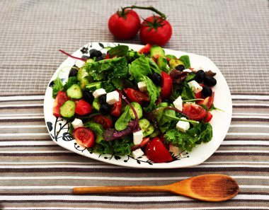 Kiraz domates, roka ve çeşitli otlar karışımı ile parlak taze yaz salatası, beyaz peynir büyük beyaz tabakta salata küçük parçalara kesilir