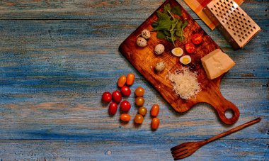 Gıda arka plan kopya alanı ile. Domates kiraz, parmesan peyniri, bıldırcın yumurtası ve salata eski köy masada. Eski mutfak eşyaları ile İtalyan ülke mutfak. Rustik tarzı. Üstten görünüm. Seçici odak