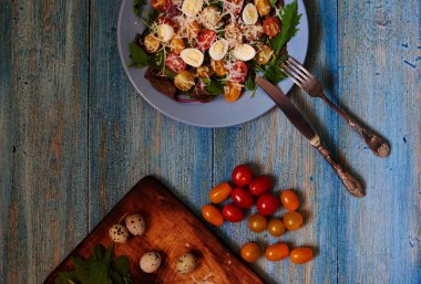 Yeşil ışık salata ve ana yemek önce bir şeyler atıştırmak için taze domates, gümüş çatal ve bıçak mavi plaka renk mavi vintage tablo bir tabakta servis salata hazır