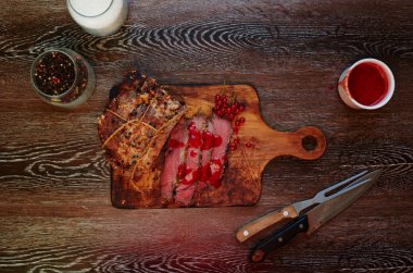 The meat medium rare with blood, lying on a wooden board where the cook cut it into pieces a la carte, served with meat is cooked vegetables on the grill clipart