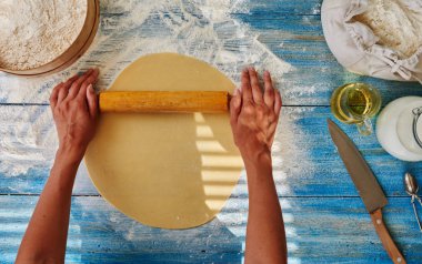 Hamur ekmek, pizza ve pasta tarifi ev yapımı hazırlık. Bayan baker haddeleme hamuru oklava ile eller. Gıda ingridients düz mutfak masasının üstünde yatıyordu. Pasta veya pişirme ile çalışma. Üstten görünüm.