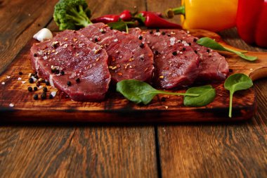 Sığır filetosu biftek ile baharat ve sebzeler ahşap tahta üzerinde. Bell ve biber biber, ot, tuz. dengeli beslenme, protein ve lif oncept. Üstten görünüm kopya alanı ile. Vintage tarzı.