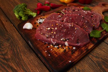 Sığır filetosu biftek ile baharat ve sebzeler ahşap tahta üzerinde. Bell ve biber biber, ot, tuz. dengeli beslenme, protein ve lif oncept. Üstten görünüm kopya alanı ile. Vintage tarzı.