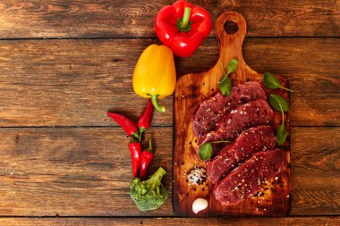 Sığır filetosu biftek ile baharat ve sebzeler ahşap tahta üzerinde. Bell ve biber biber, ot, tuz. dengeli beslenme, protein ve lif oncept. Üstten görünüm kopya alanı ile. Vintage tarzı.