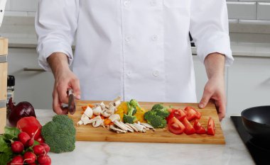 Dilimlenmiş sebze ve mantar salata ve sıcak yemekler, modern bir parlak mutfak aşçıdır