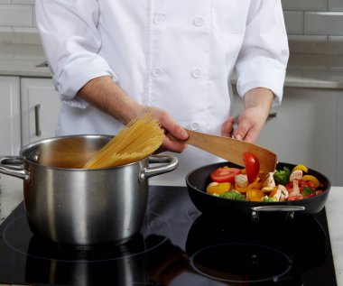 Adam plakayı ayakta cook, cook makarna ve koyar sebze ve mantar bir tavada
