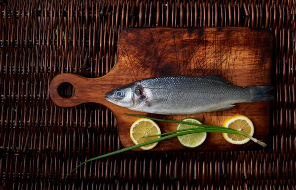 Limon dilimleri ve soğan bir kesme tahtası deniz tuzu yanında yatan Levrek Marine