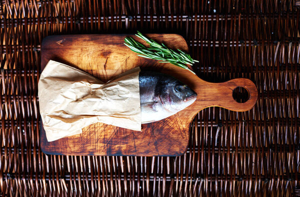 Seller fishmongers packed fresh fish in paper. Fresh fish wrapped in brown paper lying on a cutting board