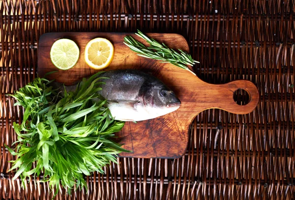 İki karanfil, limon ve tarhun fışkın a bohça-in biberiye yanındaki masada küçük bir kuş Dorado yatıyor
