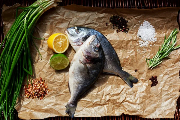 Pişirme için kahverengi kağıt üzerinde ortaya konulan iki taze Dorada Cook daha sonra Marine kağıt taze balık koymak.