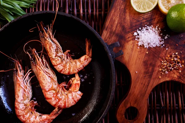 Kireç ve otlar restoranda tereyağında kızarmış sıcak bir dökme demir üzerinde kaplan karides kavrulmuş. Pişirme işlemi. Izgara karides. Zarif yemek deniz ürünleri. Gıda arka plan. Seçici odak.