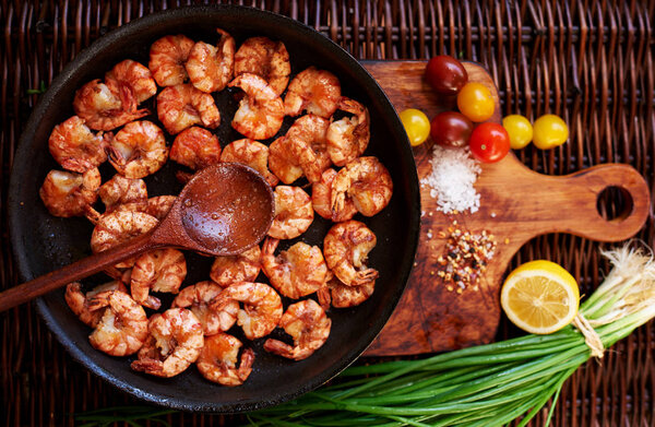 The composition of the shrimp in a large black skillet, just fried over high heat in a large sauce with sea salt, spices.