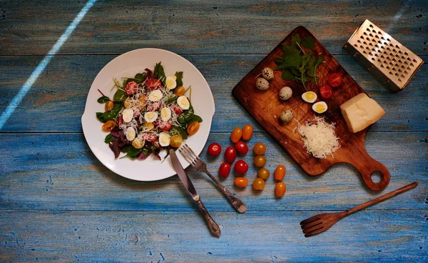 在木桌上是一个老式的蓝菜与一个清淡的夏季沙拉新鲜的绿色西红柿和鹌鹑蛋 充满酱油和橄榄油 — 图库照片