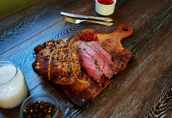 Mavi nadir, yabani çilek et sosu yanında duran bir kesme tahtası üzerinde aşçı hizmet kadar iştah açıcı Dana Bonfile fırında pişmiş