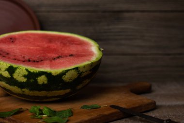 Dilimler ve ahşap tahta üzerinde taze karpuz yarısı.