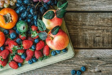 Vintage ahşap tepsi ve ahşap masada taze meyve. Taze organik meyveler. Üst te. Kopyalama alanı.