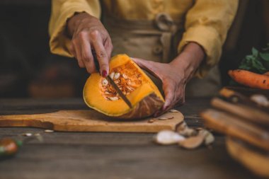 Mutfak bıçağı ve lezzetli vejetaryen yemek için mantar ve sebze malzemelerle rustik kesme tahtası üzerinde doğranmış kabak, koyu tarz.