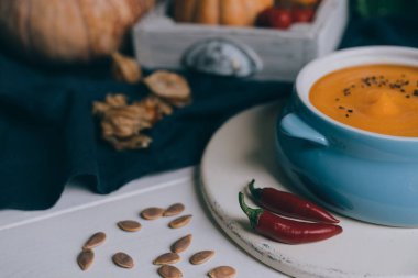 Sonbahar sebze ve kabak çekirdeği ile bir kapta kabak çorbası. Vegan çorbası. Sebze krema çorbası ve malzemeler. Sağlıklı beslenme veya vejetaryen gıda kavramı. Tonlu görüntü. Seçici odaklama.