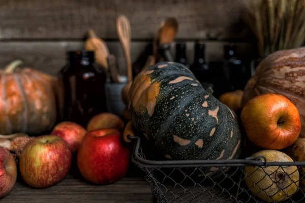 Autumn pumpkins Thanksgiving background. Orange, yellow and green pumpkins over wooden table. Different size pumpkins with apples, corn on wooden background. Harvest vegetables. Toned image.