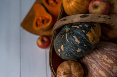 Beyaz rustik tahtalarda sonbahar sebze. Vintage hasır sepet sonbahar süslemeleri. Kabak, kabak, kabak ve elma ile bir bereket. Kopya alanı ile tonlu görüntü. Seçici odak. Hasat zamanı.