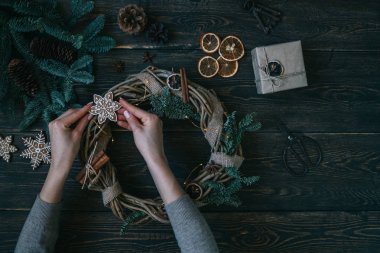 Süslemeleri, çelenk ve çam kozalağı ile Noel arka plan. Koyu vintage ahşap tahta üzerinde noel ağacı dalları ve kuru baharat yapılmış çelenk oluşturma. Yeni Yılınız Kutlu Olsun. Tonlu görüntü. Yumuşak odaklama.
