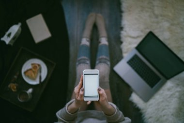 Woman using smartphone for browsing internet store at home. Online shopping conceptspace for text. Mood winter. Seasonal holidays. Merry Christmas and New Year. Top view. Toned image. Selective focus.