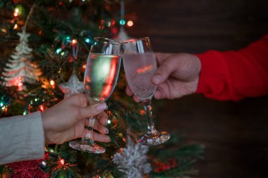 Noel ağacının yanında tatil ve birliktelik. Mutlu Noeller ve Mutlu Yıllar! Noel partisi zamanı. Şampanyayla kadeh kaldıran bir çift. Kutlama konsepti, tatil arka planı, seçici odak.