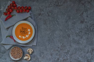 Geleneksel sonbahar yemekleri, kabak çekirdeği ve gri taş masada krem ile sıcak ve baharatlı kabak çorbası. Sonbahar yemeği. Organik sebzeler ve sağlıklı gıda konsepti. Kopyalama alanı ile üst görünüm. Tonlu görüntü