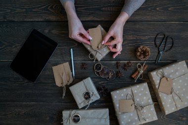 El yapımı Noel hediyeleri yaparken tablet kullanan bir kadın. Çevrimiçi öğrenme. Mutlu tatiller için hazırlık konsepti. Şölen dekoru. Kopyalama spazmı ile üst görünüm. Tonlanmış görüntü. Klasik stil.