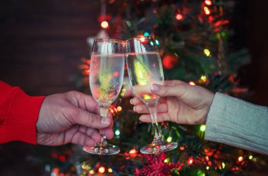 Noel aydınlatmaları ve şampanya bardağı. Bardak şampanya, kutlama ve Noel ve mutlu yeni yıl onuruna kızartma insanlarla elleri. Şampanya flüt ile tezahürat çift.