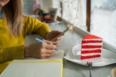 Kafede kek ile kapuçino fincan. Sıcak içecek. Kışın rahat bir kafe atmosferi. Kahve zamanı konsepti. Kadın serbest çalışan e-posta kontrol ederken içecek zevk. Tonlu görüntü. Seçici odaklama.