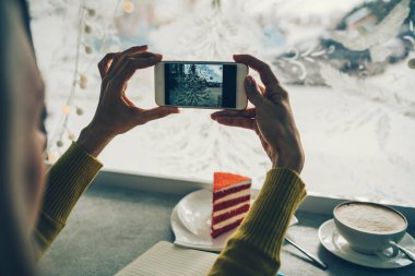 Kişi bir akıllı telefon ile fotoğraf çekiyor. Kahve dükkanında akıllı telefon kullanan kadın ellerinin yakın çekim görüntüsü, arama veya sosyal ağlar konsepti, hipster kız arkadaşlarına bir görüntü gönderir.