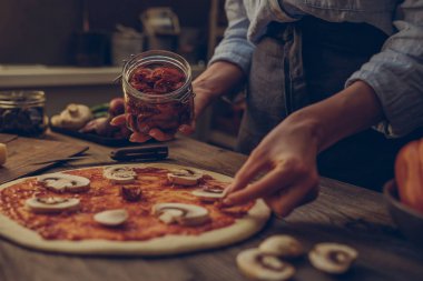 Ellerini pişir. Ellere yakın, masanın etrafında bazı malzemeler. Taze orijinal İtalyan çiğ pizza, geleneksel tarzda hazırlık. Malzemeler ve baharatlar ahşap masada ev yapımı pizza yapmak için.